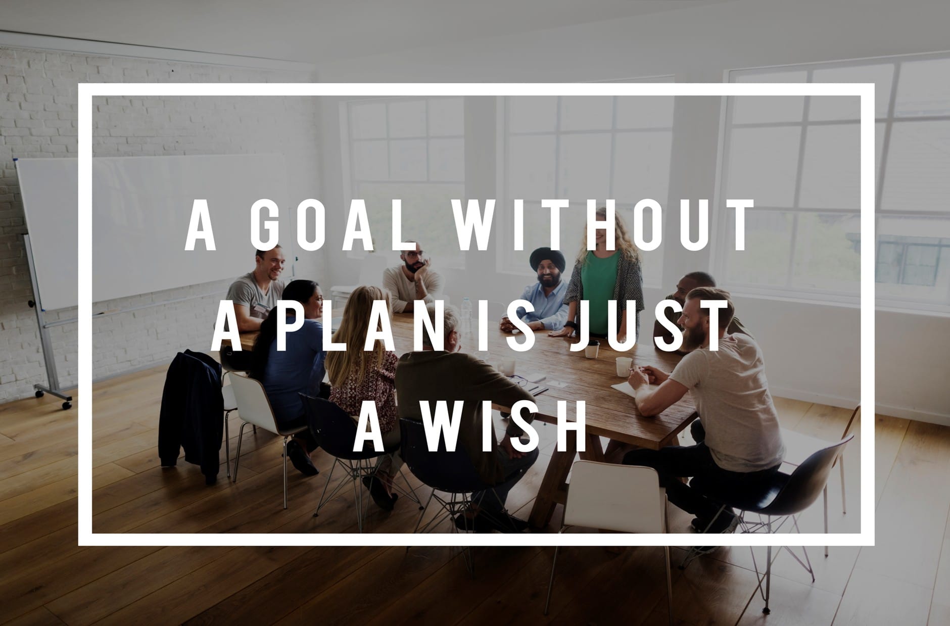A group of people in a meeting room discussing a motivational quote about goals and plans.